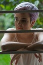 Beautiful violet short-haired girl behind a fence looking at her Royalty Free Stock Photo