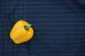 Beautiful vivid yellow bell pepper minimal flat lay on checked tea towel abstract texture background. Royalty Free Stock Photo