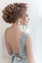 Beautiful volume hairstyle for a bride in a gentle blue light dress with large earrings and adornment in hair
