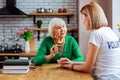 Beautiful volunteer consoling aged woman in green wool sweater