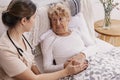 Beautiful volunteer is holding an elderly woman`s hand at the hospital