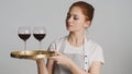 Beautiful waitress in apron confidently holding tray with red wine glasses over white background Royalty Free Stock Photo