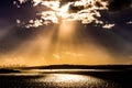 Beautiful and warm evening clouds with sunbeams shining on the water and the skyline of sydney in the back