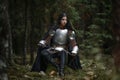 A beautiful warrior girl with a sword wearing chainmail and armor in a mysterious forest. Royalty Free Stock Photo