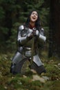 A beautiful warrior girl with a sword wearing chainmail and armor in a mysterious forest. Royalty Free Stock Photo