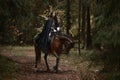 A beautiful warrior girl with a sword wearing chainmail and armor riding a horse in a mysterious forest.