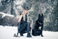 Warrior woman in image of viking with ax and horned helmet next to the big black dog in winter forest Royalty Free Stock Photo