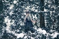 Beautiful warrior woman in image of viking with horned mask helmet and two axes in winter snowy forest