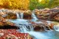 Beautiful waterfall in forest at sunset. Autumn landscape, fallen leaves Royalty Free Stock Photo