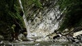 Beautiful waterfall in green forest. Creative. Mother and boy crossing tropical river in mountain jungle. Royalty Free Stock Photo