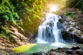 Beautiful waterfall at the mountain with blue sky and white cumulus clouds. Waterfall in tropical green tree forest. Waterfall Royalty Free Stock Photo