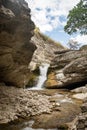 A beautiful waterfall in a mountain gorge with rocks and clear water on a sunny summer day. Royalty Free Stock Photo