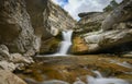 A beautiful waterfall in a mountain gorge with rocks and clear water on a sunny summer day. Royalty Free Stock Photo