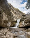 A beautiful waterfall in a mountain gorge with rocks and clear water on a sunny summer day. Royalty Free Stock Photo