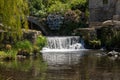 Beautiful waterfall, stream, willow tree and old stone bridge. Royalty Free Stock Photo