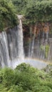 a beautiful waterfall under Mount Semeru and covered in a beautiful rainbow