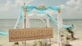 Beautiful wedding arch on the beach. Wooden nameplate with the names of the bride and groom. Wedding day.