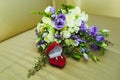 Beautiful wedding bouquet of blue roses and wedding rings of the bride and groom in a red box in the form of a heart Royalty Free Stock Photo