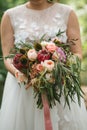 A beautiful wedding bouquet with eucalyptus, roses and exotic flowers in the hands of the bride in a wedding dress. Royalty Free Stock Photo