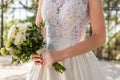 Beautiful wedding bouquet of flowers in hands of the bride. Bride holding elegant bouquet made of white roses and greenery. Royalty Free Stock Photo