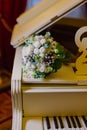 A beautiful wedding bouquet of golden rings of the newlyweds lie on the surface of a white piano. Wedding day. overall Royalty Free Stock Photo