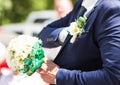 Beautiful wedding bouquet in hands of the groom. Gift to the bride.Blue classic designer suit with buttonhole. Royalty Free Stock Photo