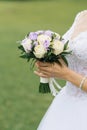 Beautiful wedding bouquet with milk roses and lilac eustoma in the hands