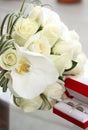 Beautiful wedding bouquet of roses and orchids and red velvet box with gold and platinum wedding rings Royalty Free Stock Photo