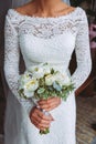 Beautiful wedding bouquet with white roses and peonies. In a bride hands in narrow, elegant white dress Royalty Free Stock Photo
