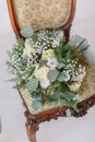 Beautiful wedding bouquet with white roses, pine and eucalyptus lying on the vintage chair. Royalty Free Stock Photo