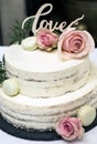 Beautiful wedding cake with cream With text Love on top pink flowers roses Royalty Free Stock Photo