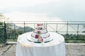 A beautiful wedding cake in four levels is on the table against the background of the picturesque lake Royalty Free Stock Photo