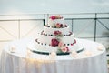 A beautiful wedding cake in four levels is on the table against the background of the picturesque lake Royalty Free Stock Photo