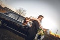 Beautiful wedding couple in the countryside next to the retro car. man groom is taking holding bride in his arms. smiling happy ch Royalty Free Stock Photo