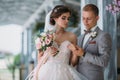 Beautiful wedding couple hugging in park with green trees on background. Groom in a business gray suit, white shirt in a Royalty Free Stock Photo