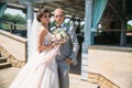 Beautiful wedding couple hugging in park with green trees on background. Groom in a business gray suit, white shirt in a Royalty Free Stock Photo