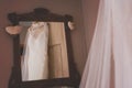 Beautiful wedding dress hanging in front of a mirror inside a bridal room