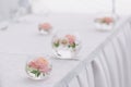 Beautiful wedding floral decoration in glass on a table in a restaurant. White tablecloths, bright room, candles, close-up shootin Royalty Free Stock Photo
