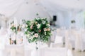 Beautiful wedding floral decoration on a table in a restaurant. White tablecloths, bright room, candles, close-up shooting. The ev Royalty Free Stock Photo