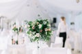 Beautiful wedding floral decoration on a table in a restaurant. White tablecloths, bright room, candles, close-up shooting. The ev Royalty Free Stock Photo