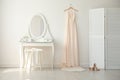 Beautiful wedding gown hanging near dressing table in room