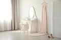 Beautiful wedding gown hanging near dressing table in room