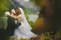 Beautiful wedding photo on mountain lake. Happy Asian couple in love, bride in white dress and groom in suit are photographed agai