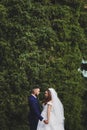 Beautiful wedding photo on mountain lake. Happy Asian couple in love, bride in white dress and groom in suit are photographed agai