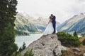 Beautiful wedding photo on mountain lake. Happy Asian couple in love, bride in white dress and groom in suit are photographed agai