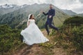 Beautiful wedding photo on mountain lake. Happy Asian couple in love, bride in white dress and groom in suit are photographed agai