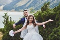 Beautiful wedding photo on mountain lake. Happy Asian couple in love, bride in white dress and groom in suit are photographed agai