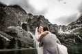 Beautiful wedding photosession. The groom circles his young bride, on the shore of the lake Morskie Oko. Poland Royalty Free Stock Photo