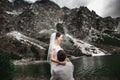 Beautiful wedding photosession. The groom circles his young bride, on the shore of the lake Morskie Oko. Poland Royalty Free Stock Photo