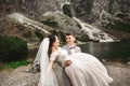 Beautiful wedding photosession. The groom circles his young bride, on the shore of the lake Morskie Oko. Poland Royalty Free Stock Photo